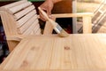 ManÃ¢â¬â¢s hand holding a brush applying varnish paint on a wooden